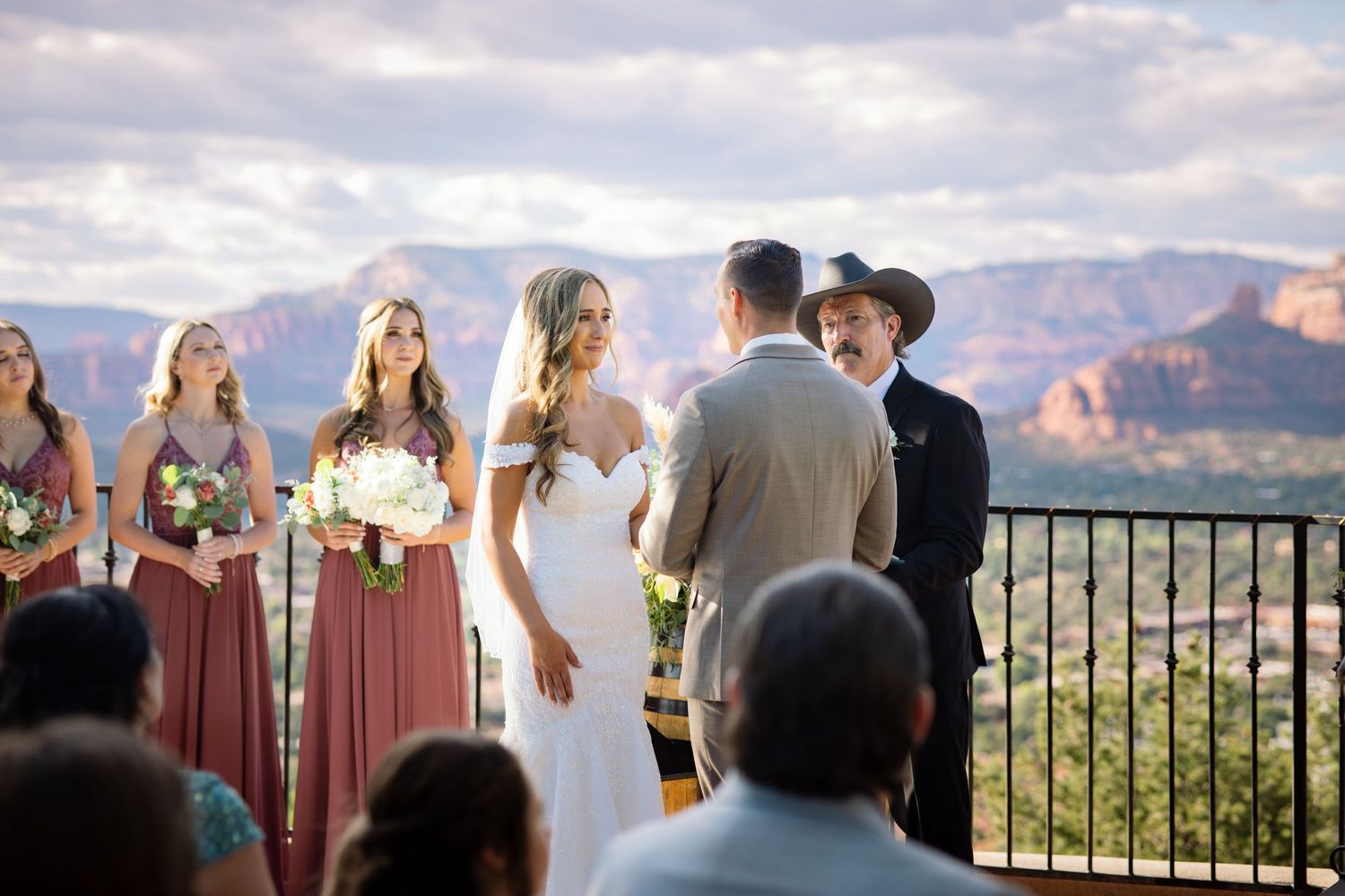 Outdoor wedding ceremony set against stunning red rock formations in Sedona with wedding party looking out at scenic vista.