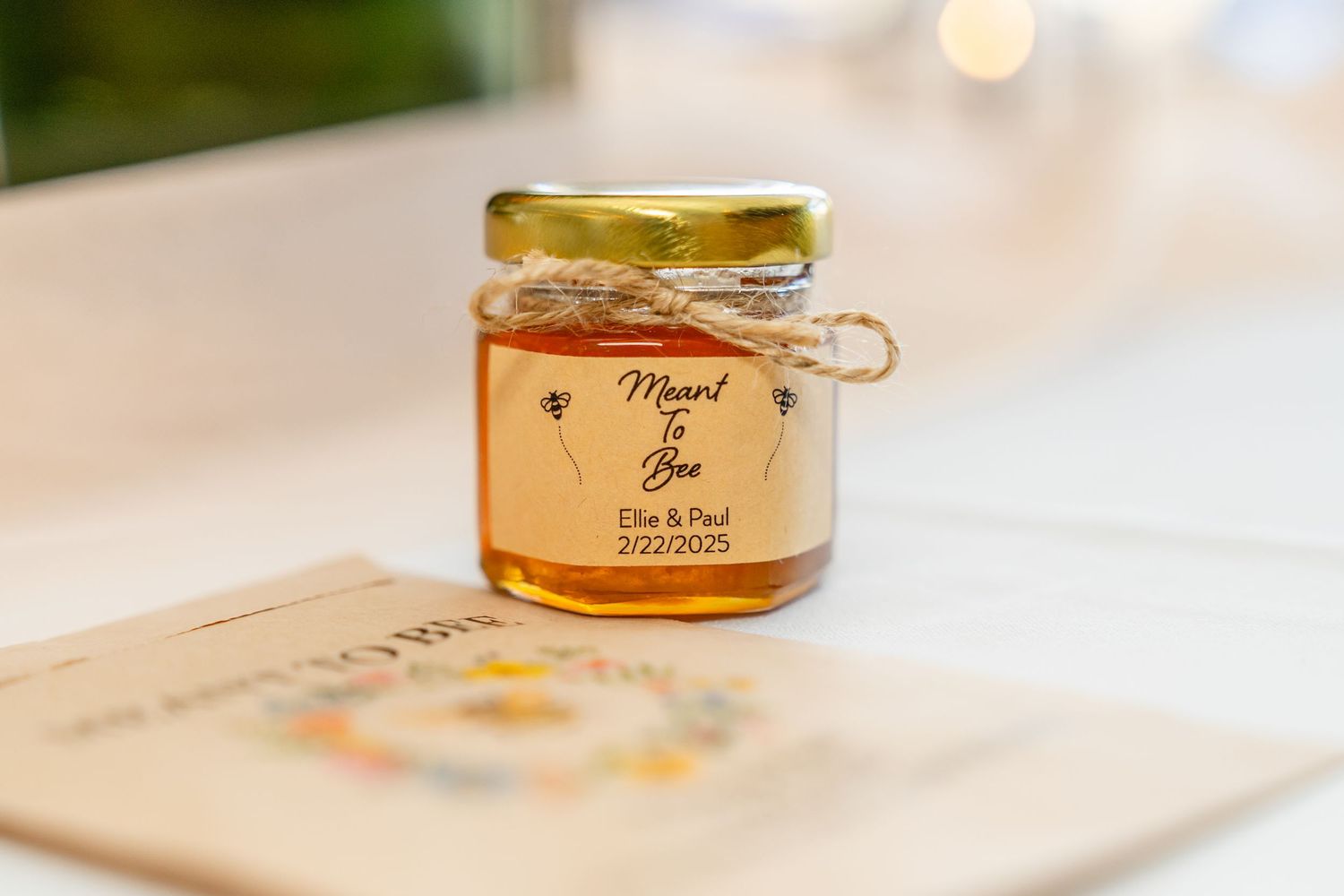 Small glass jars of honey reflect bright ambient light on a light-colored surface.