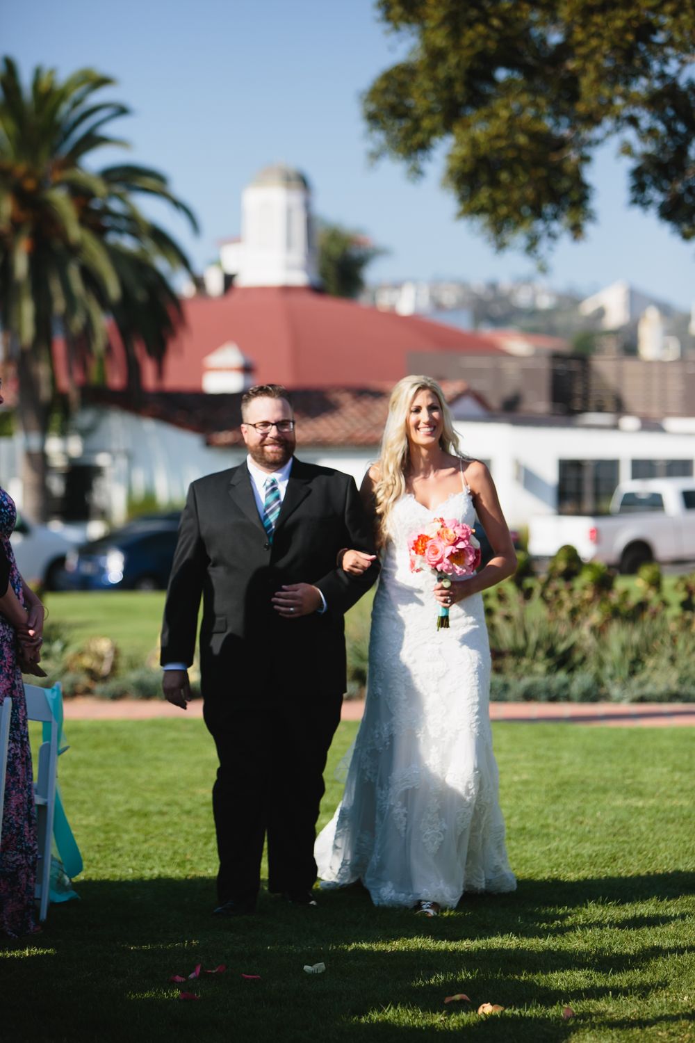 Outdoor wedding ceremony processional photos on green lawn with palm trees at Ole Hanson Beach Club in San Clemente.