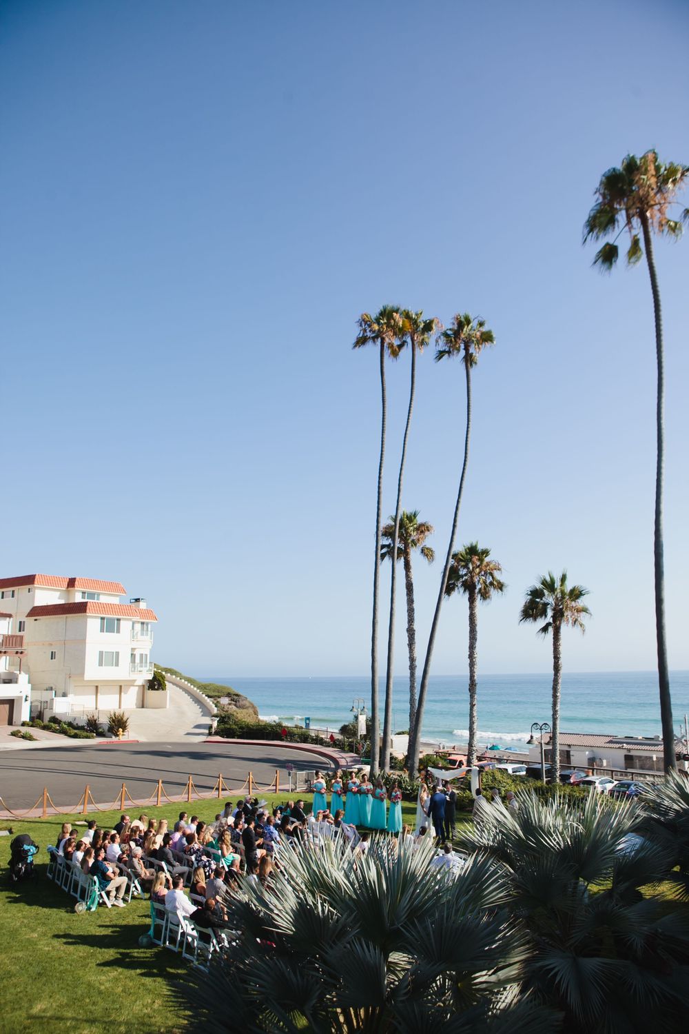 A beautiful outdoor wedding ceremony at Ole Hanson Beach Club with beautiful palm trees overlooking the ocean in Orange County, California.