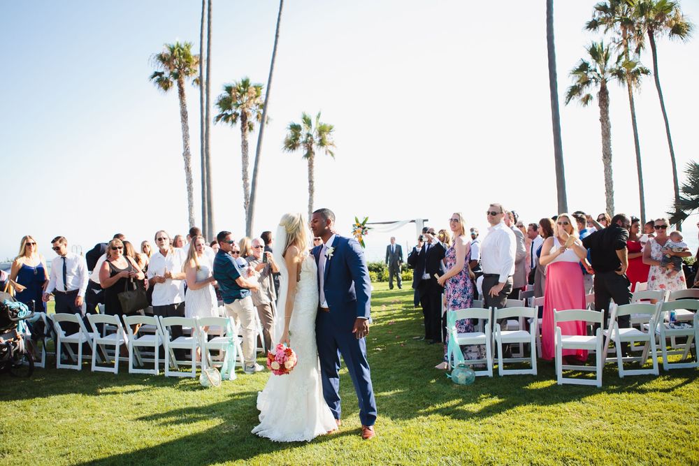 A beautiful outdoor wedding ceremony at Ole Hanson Beach Club with beautiful palm trees overlooking the ocean in San Clemente.