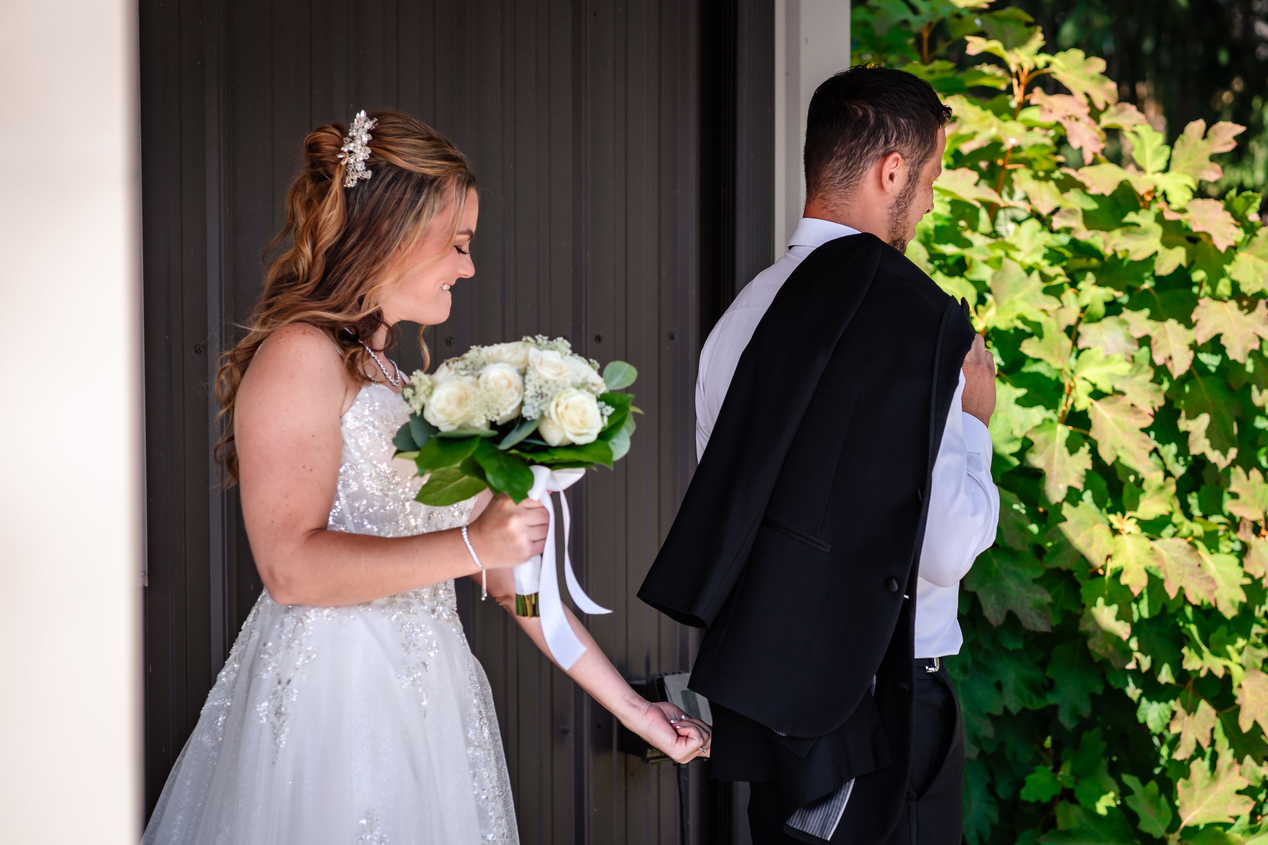 Emotional first look moment between bride and groom outside venue.