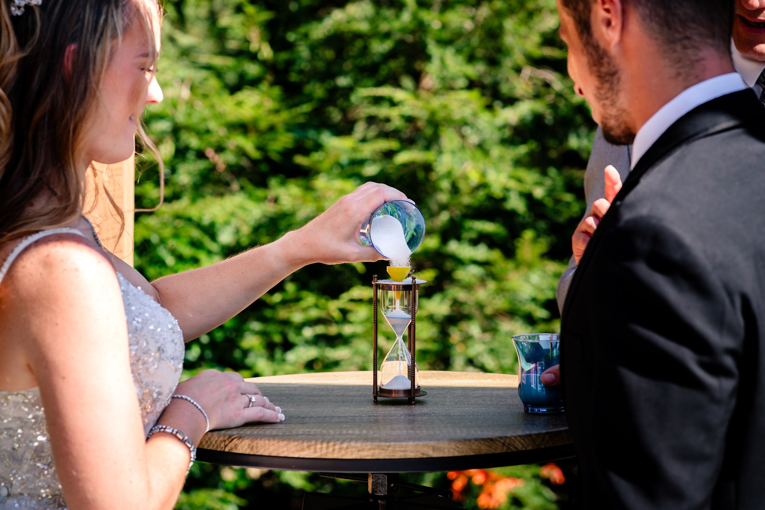 Wedding guests seated outdoors at a rustic venue with wooden barn in background.