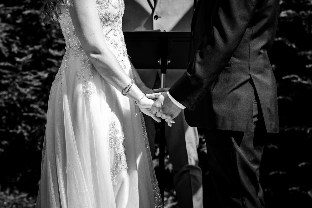 Couple signing documents at an outdoor wedding ceremony with guests watching.