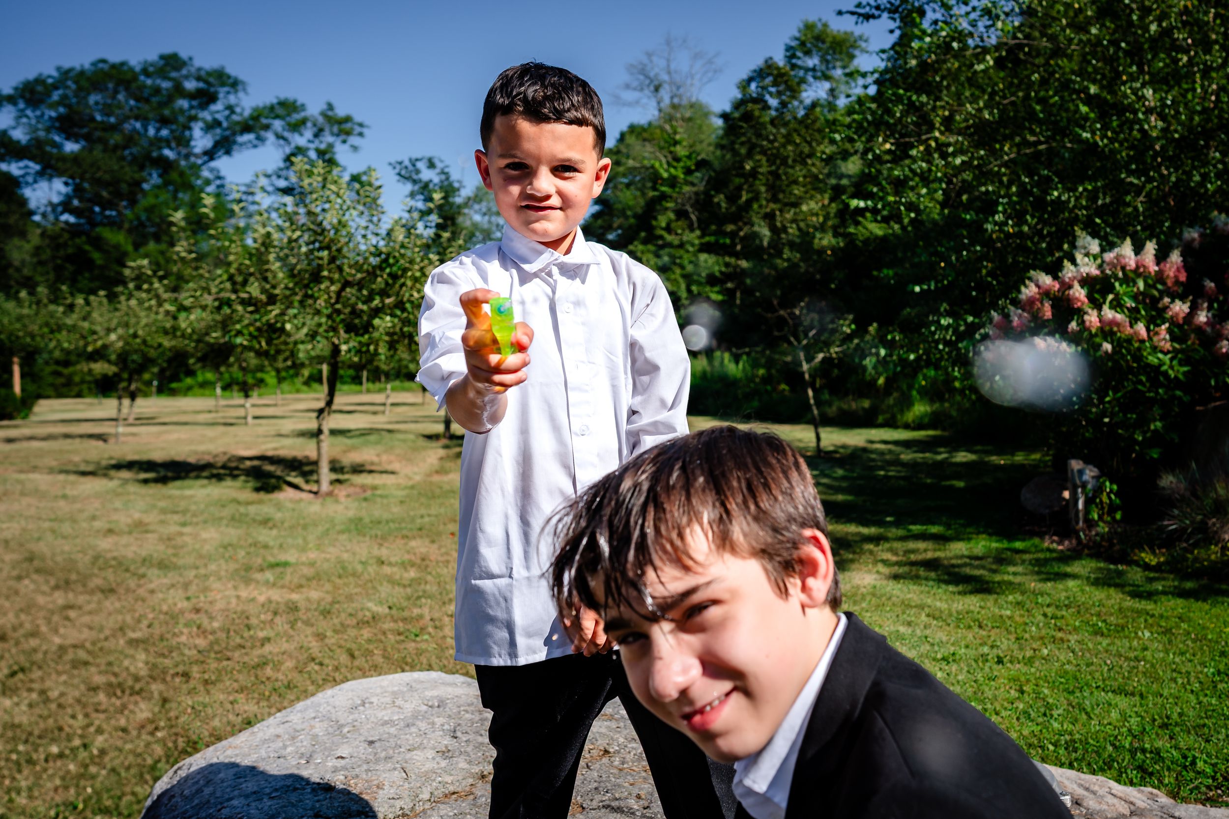 Playful groomsmen in white shirts enjoying outdoor festivities at a wedding.