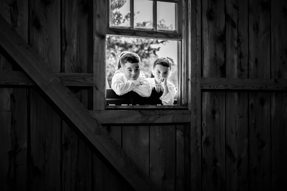 Rustic barn windows frame wedding moments in black and white photography.