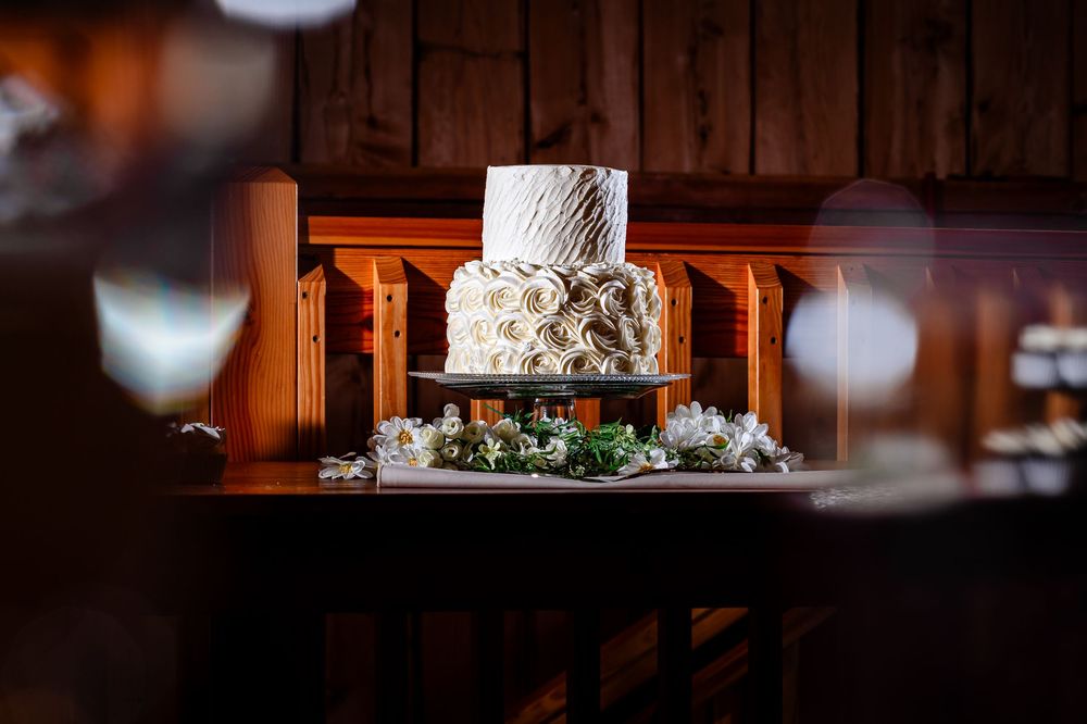 Wedding cake and floral decorations displayed in warm rustic barn lighting.