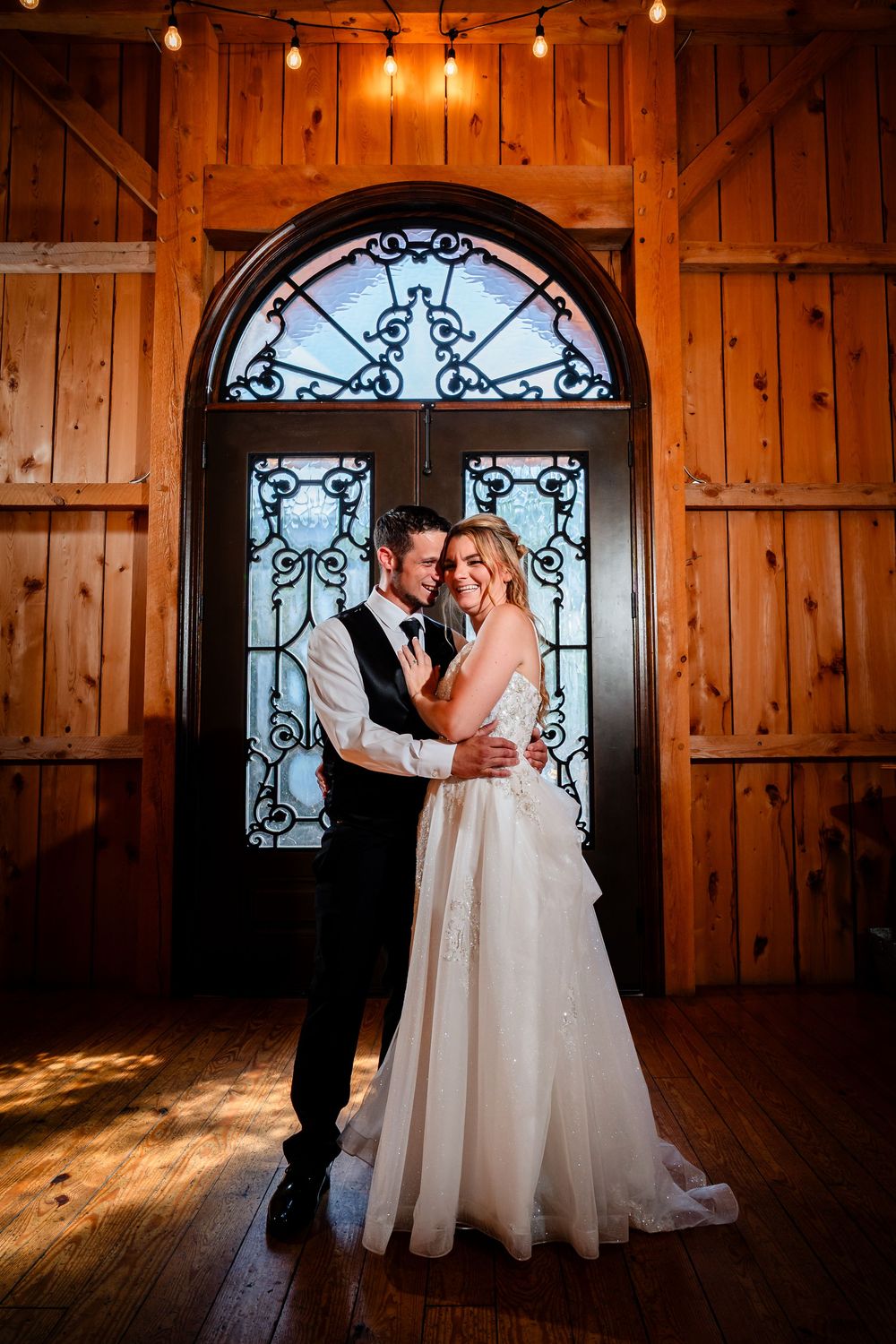 Romantic wedding photos inside rustic barn with decorative iron window details.