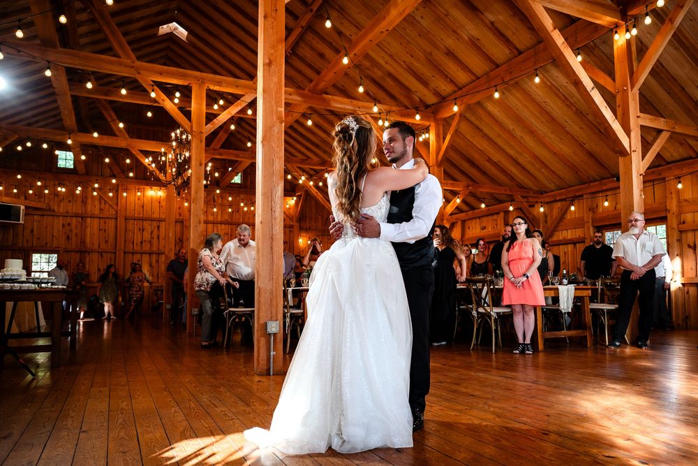 Spacious rustic barn venue decorated with string lights for wedding reception.