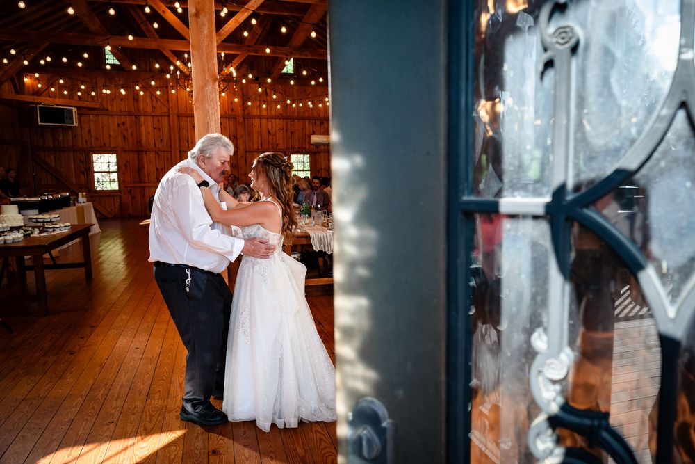 Wedding couple shares first dance under twinkling lights in rustic barn venue.