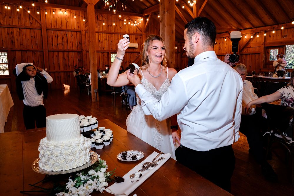 Wedding celebration in a wooden barn with string lights and guests enjoying festivities.