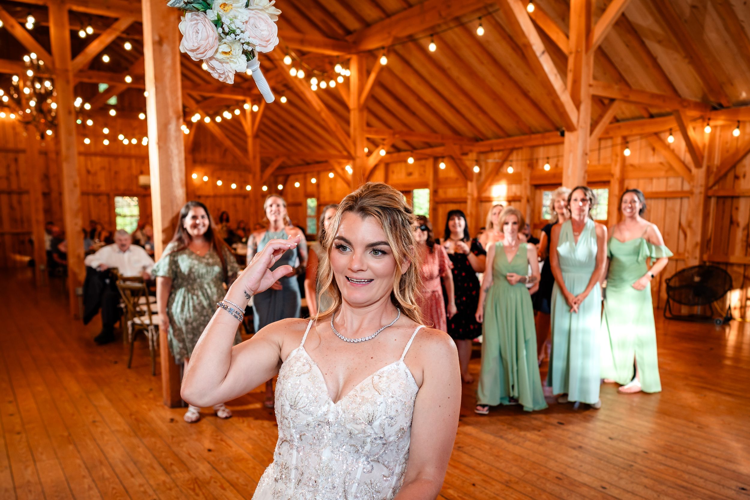 Guests celebrate at a barn wedding reception decorated with string lights and mint green accents.