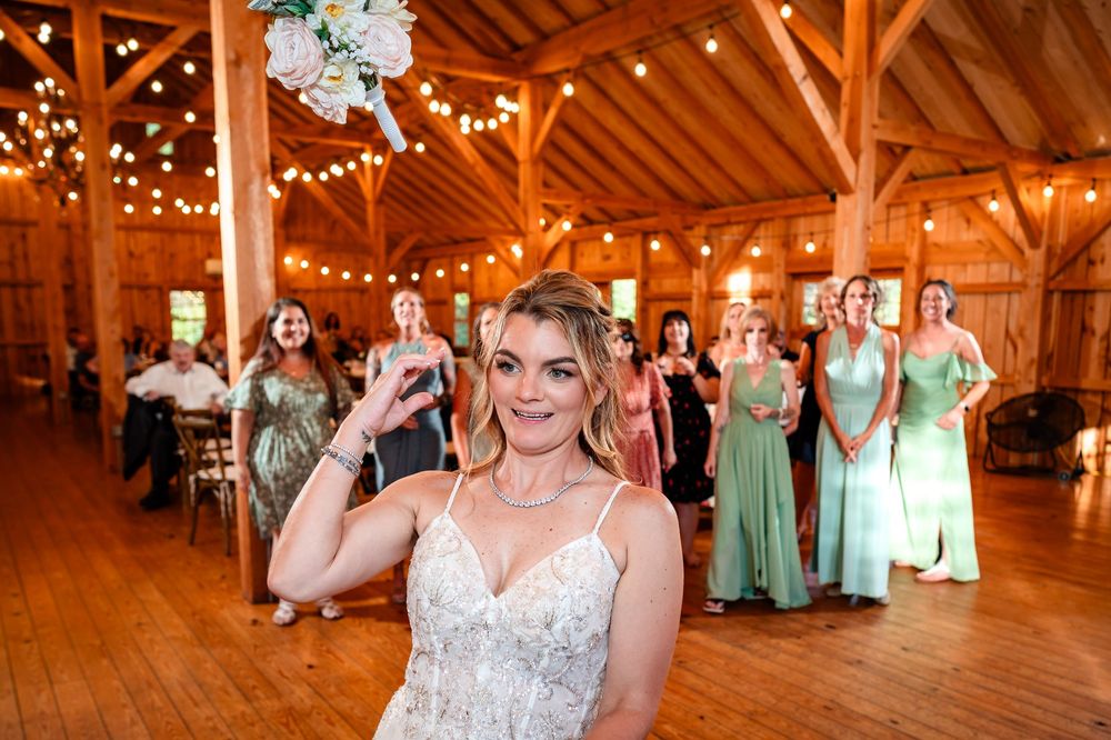 Guests celebrate at a barn wedding reception decorated with string lights and mint green accents.