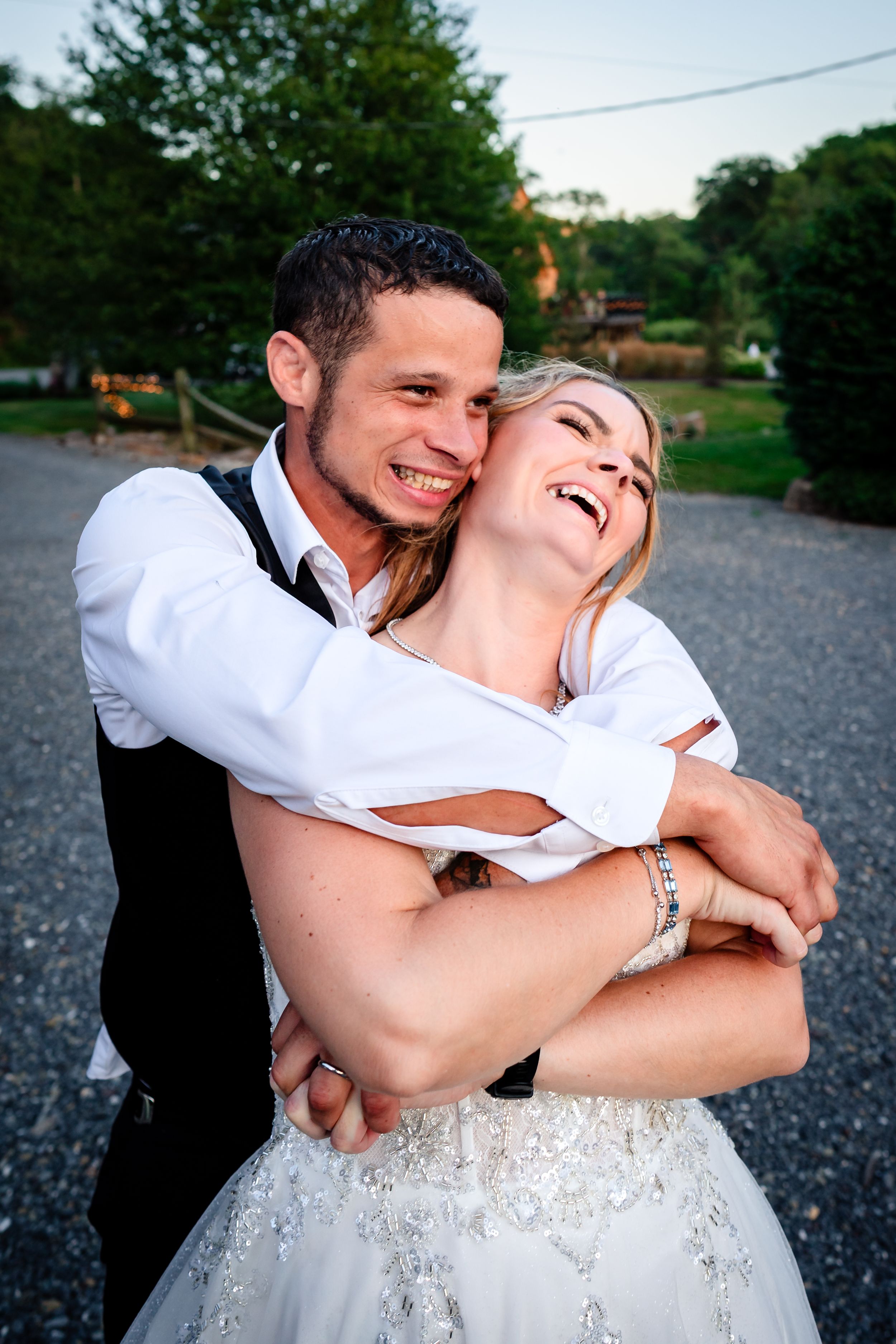 Joyful candid moment between newlyweds on gravel path.