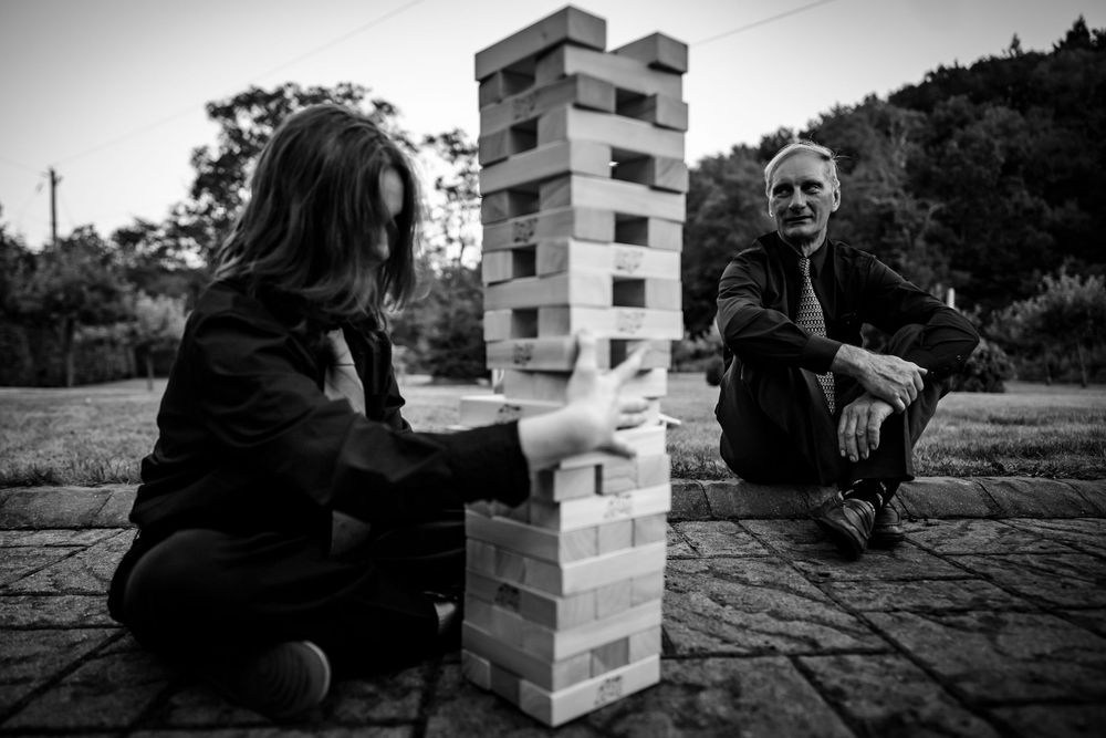 Black and white photos of wedding guests playing giant Jenga outdoors.