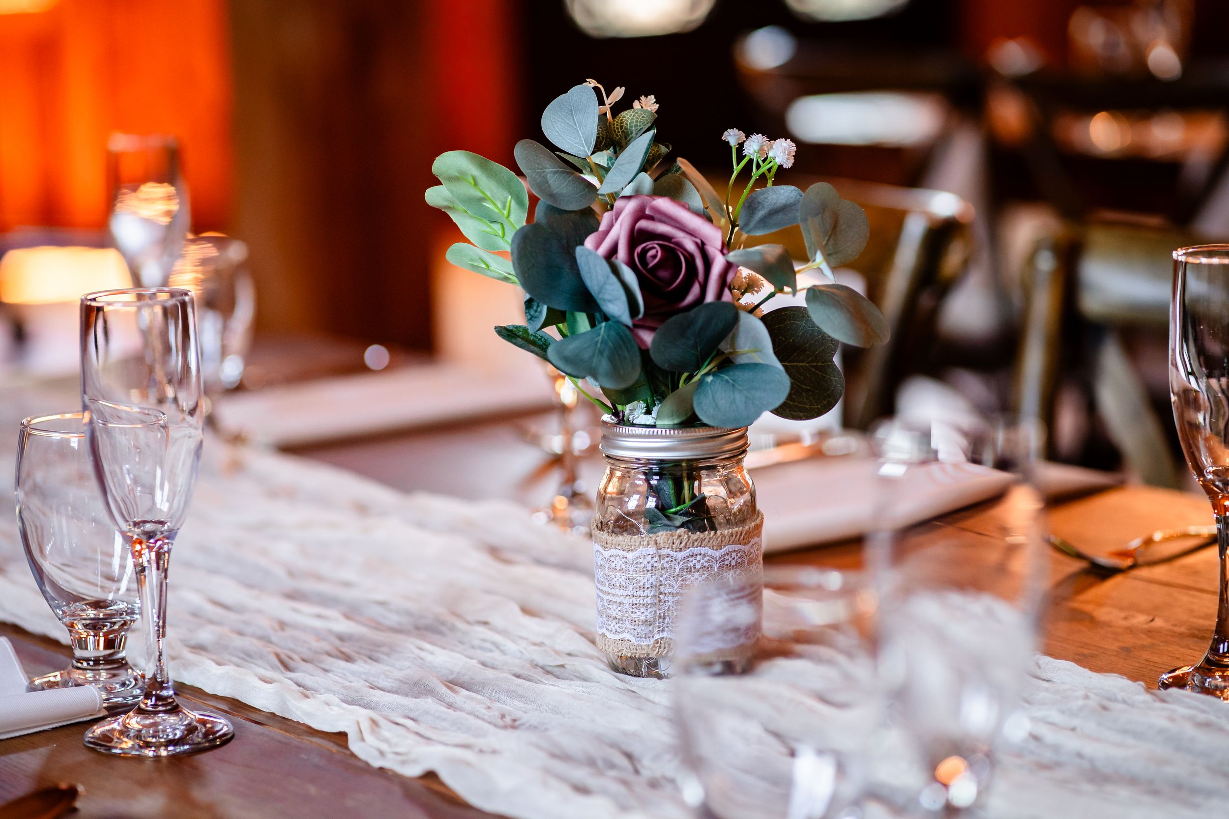 Elegant table settings with glassware and floral centerpieces at wedding reception.