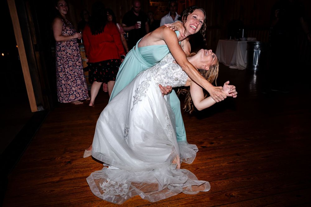 Wedding guests participate in reception games and activities on rustic wooden dance floor.