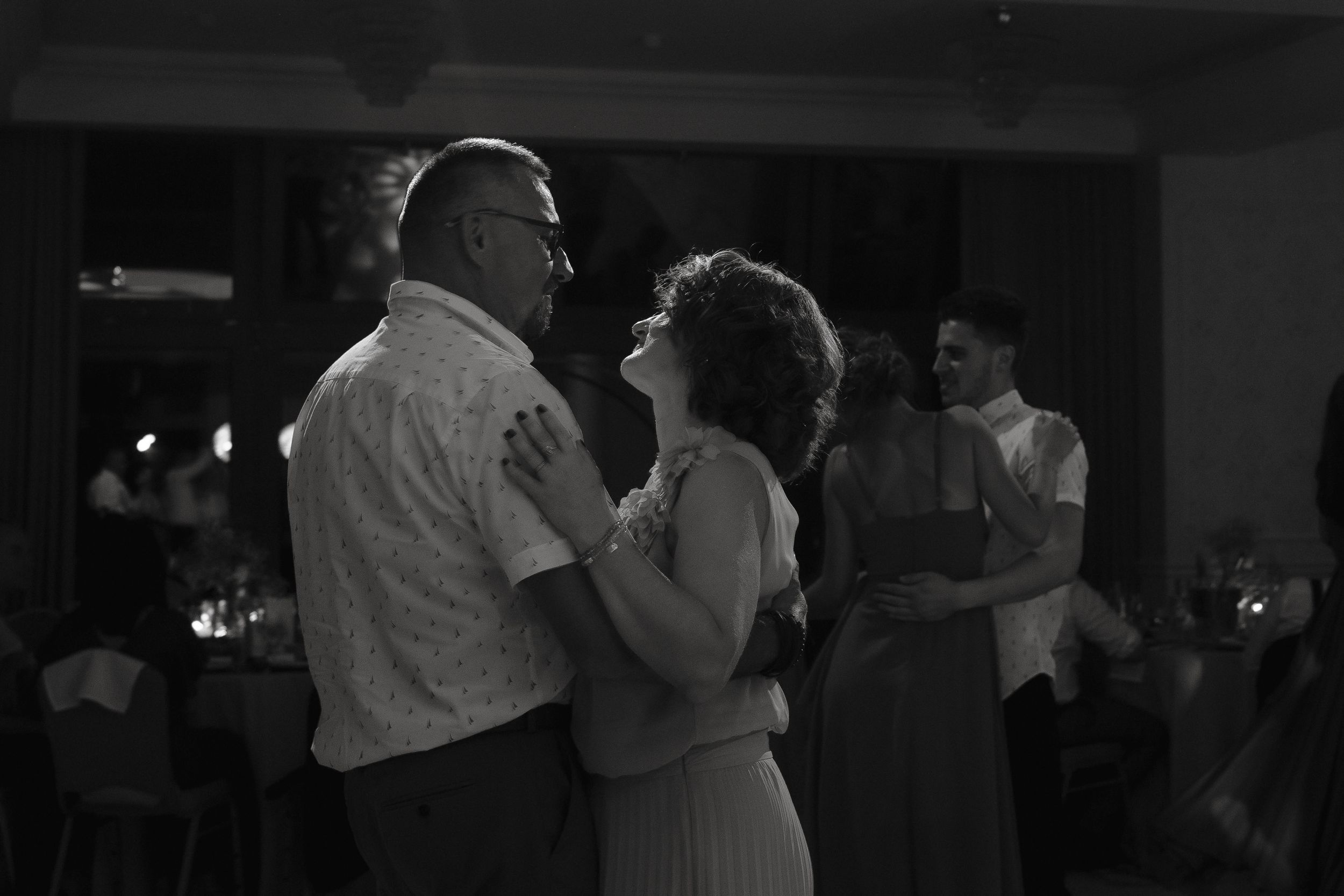 Couples slow dancing together at an evening event in black and white photography.