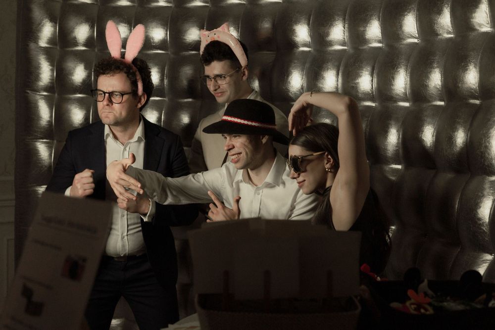 Three people wearing 3D glasses watch a screen with dramatic lighting in what appears to be a movie theater or screening room.