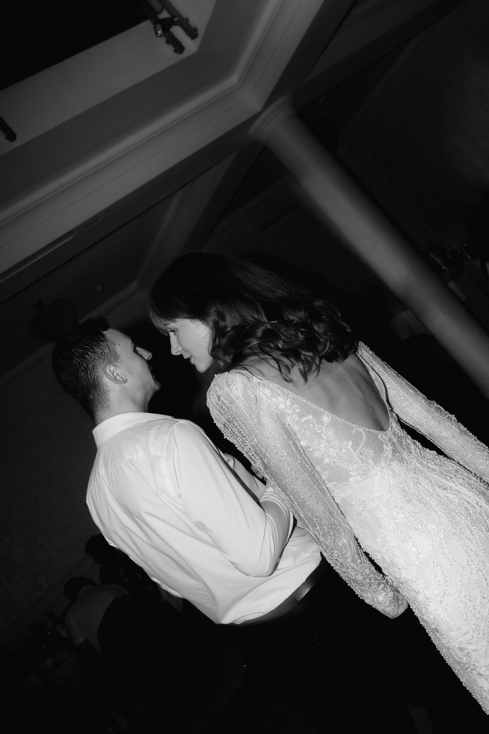 A bride and groom share an intimate dancing moment at their wedding reception in black and white photography.