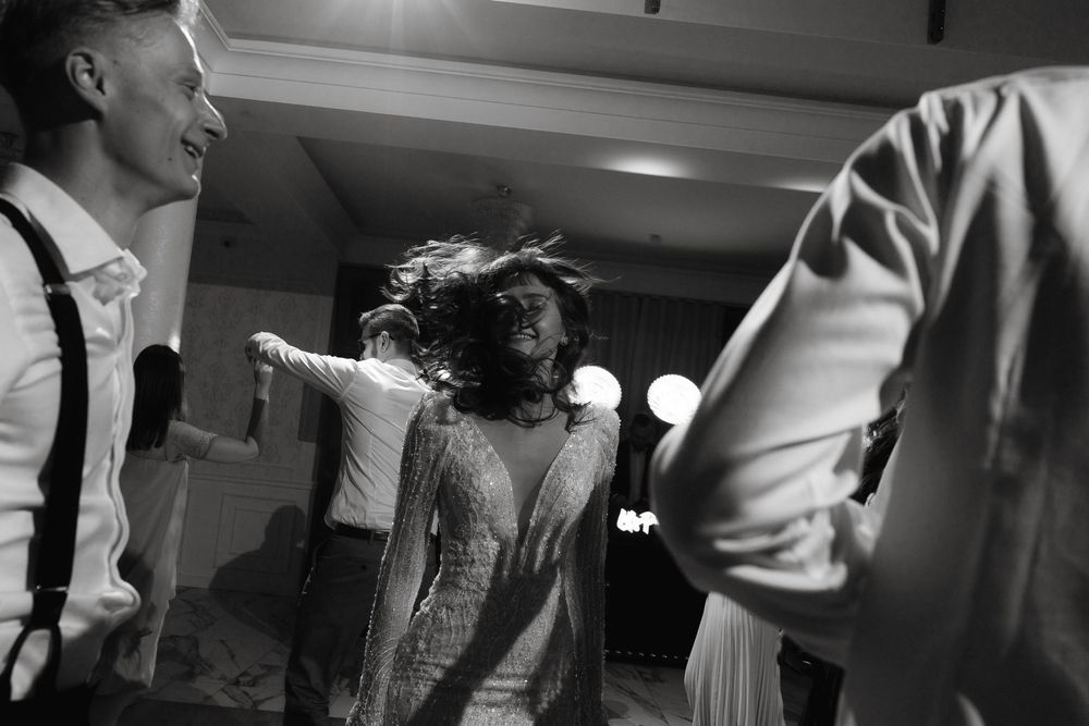 Black and white photo of people dancing and celebrating at an energetic party or reception.
