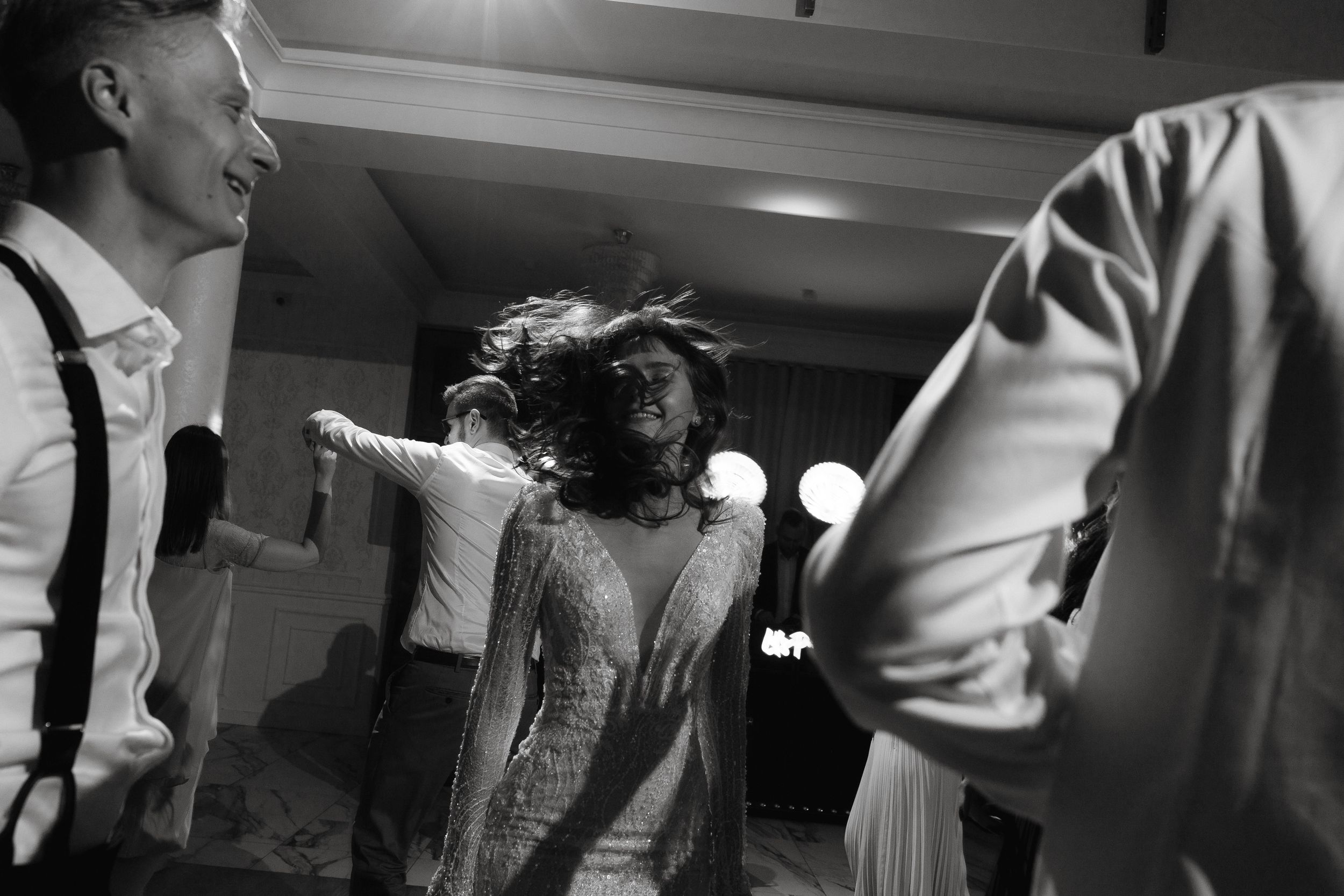 Black and white photo of people dancing and celebrating at an energetic party or reception.