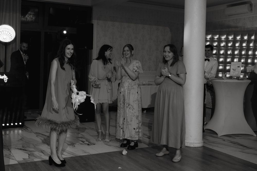 A vintage black and white photograph showing people in mid-century dresses gathered at a social event.