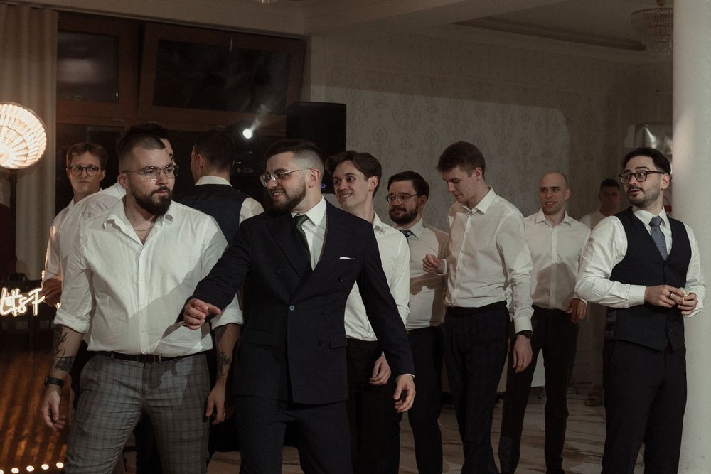 A group of people in formal attire stand in line while looking at mobile phones on their phones.