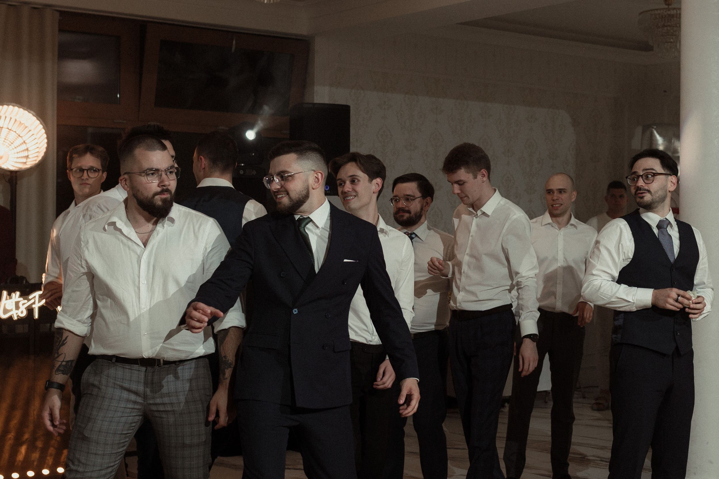 A group of people in formal attire stand in line while looking at mobile phones on their phones.