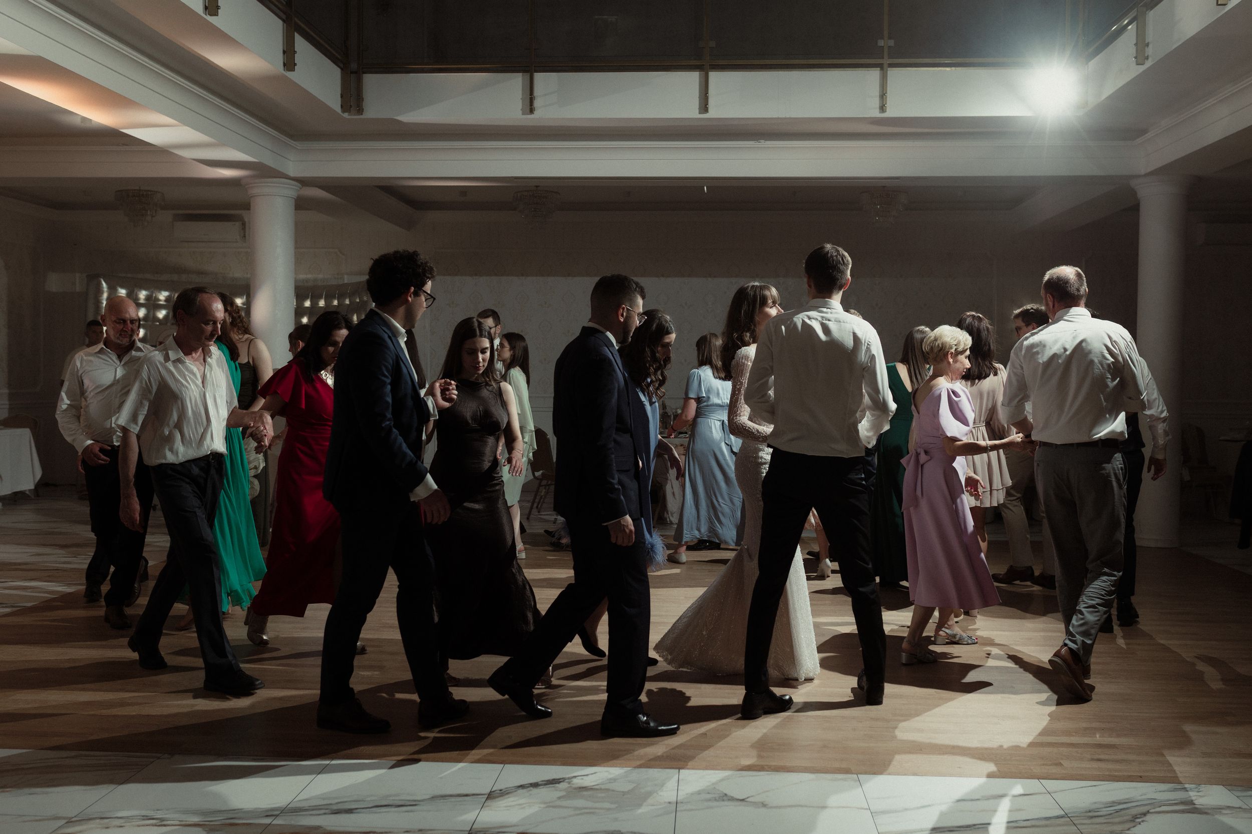 People dancing together at an evening party in an indoor venue with low lighting.