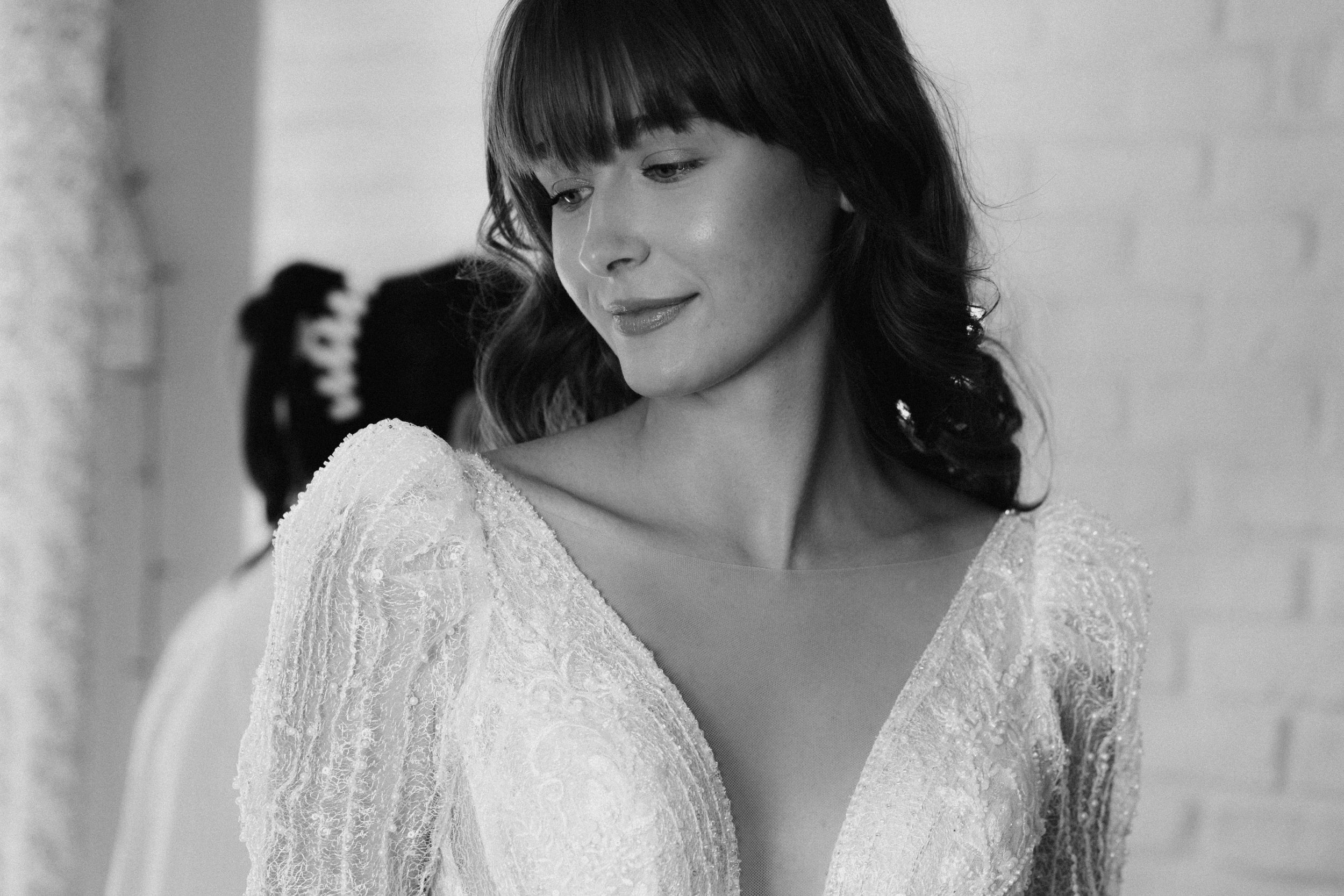 Artistic black and white photo series showing a woman in delicate lace dress against white wall.