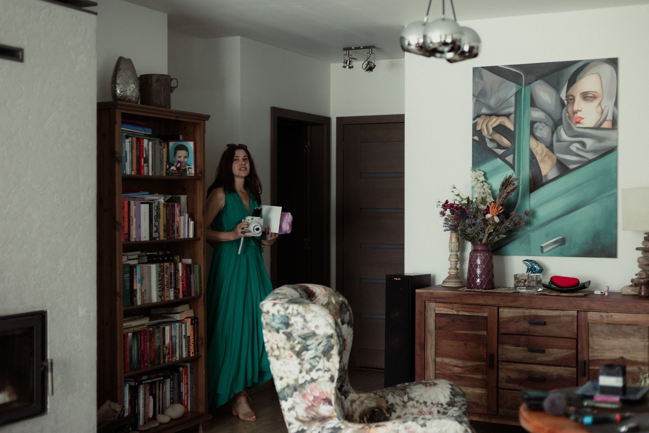 Intimate home interior with bookshelves, artwork, and furniture in natural lighting.
