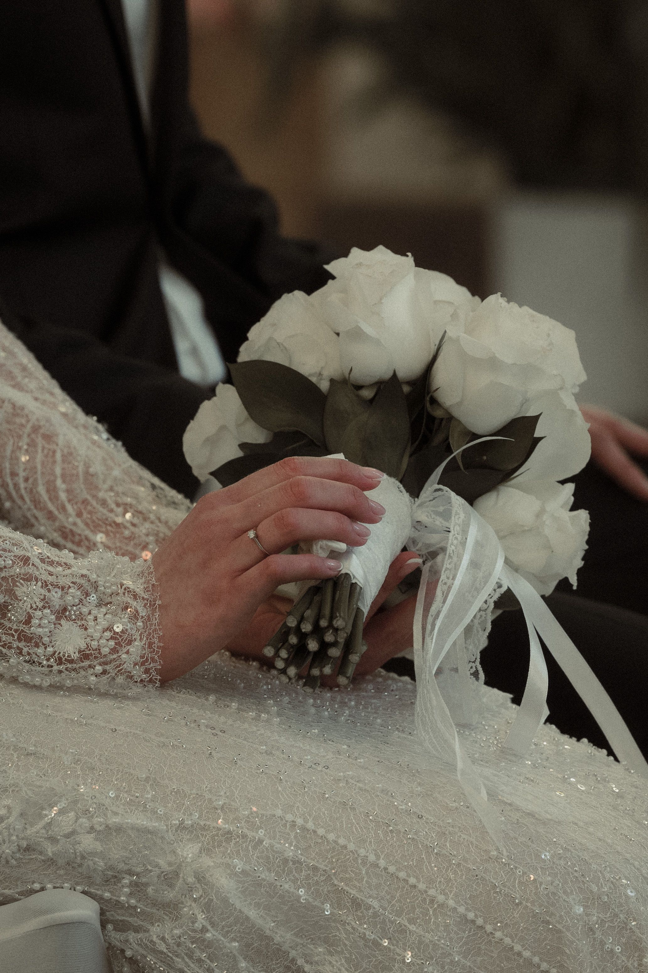 Delicate white lace fabric with floral details being carefully arranged and adjusted on a surface.