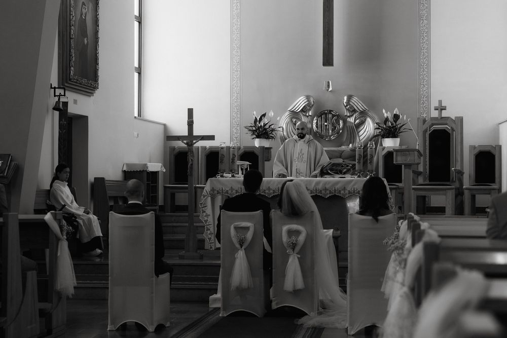 Black and white photograph showing figures in white robes performing during a church service at an altar.