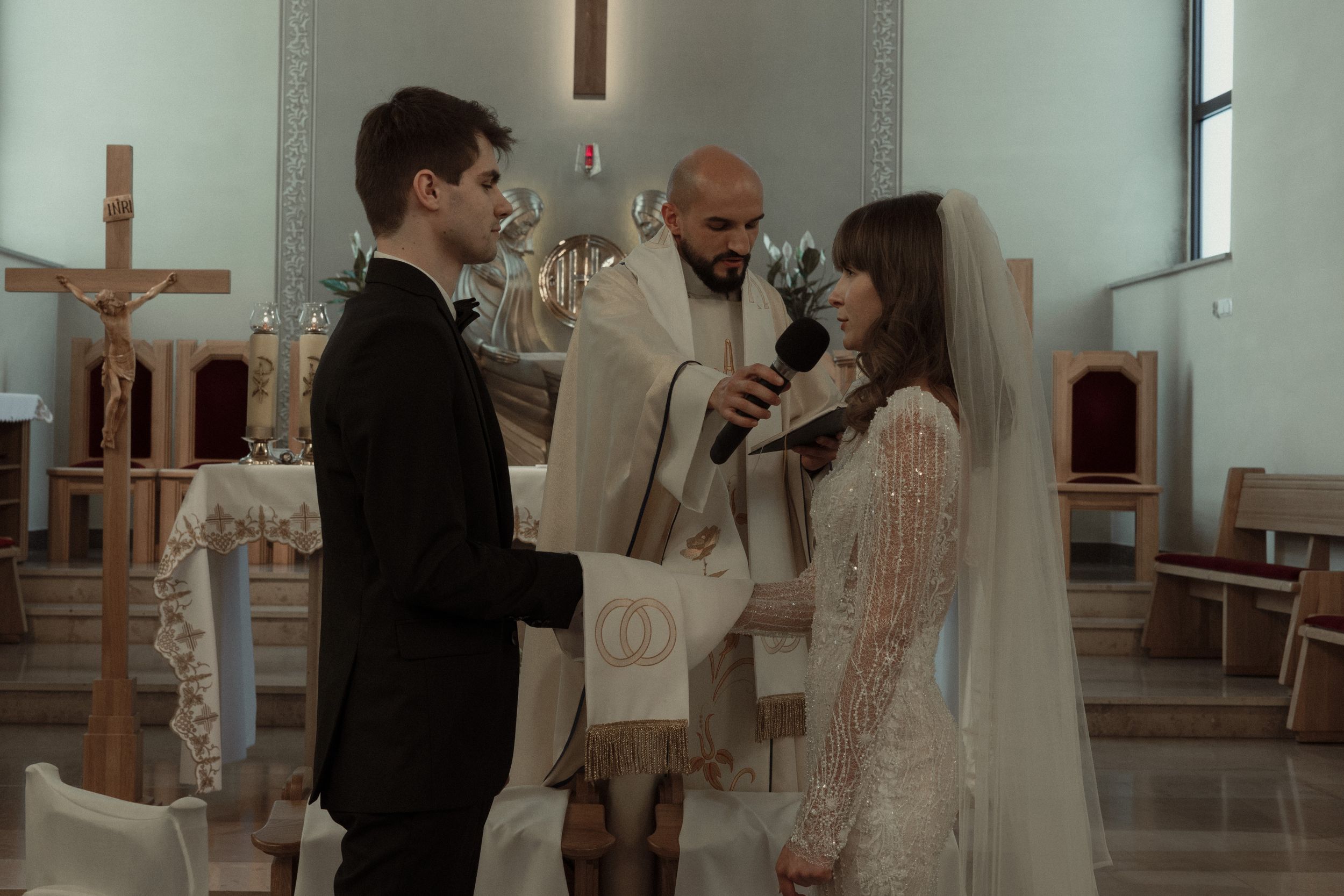 A couple exchanges vows during a church wedding ceremony as a priest officiates at the altar.
