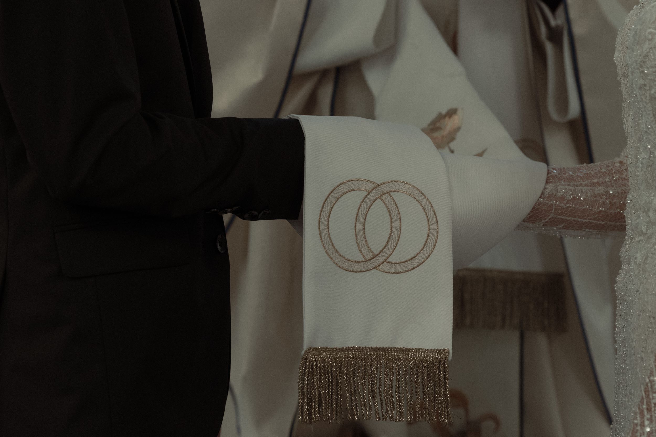 A circular double-C Chanel brand logo design in shiny metallic finish shown on a smooth dark surface.