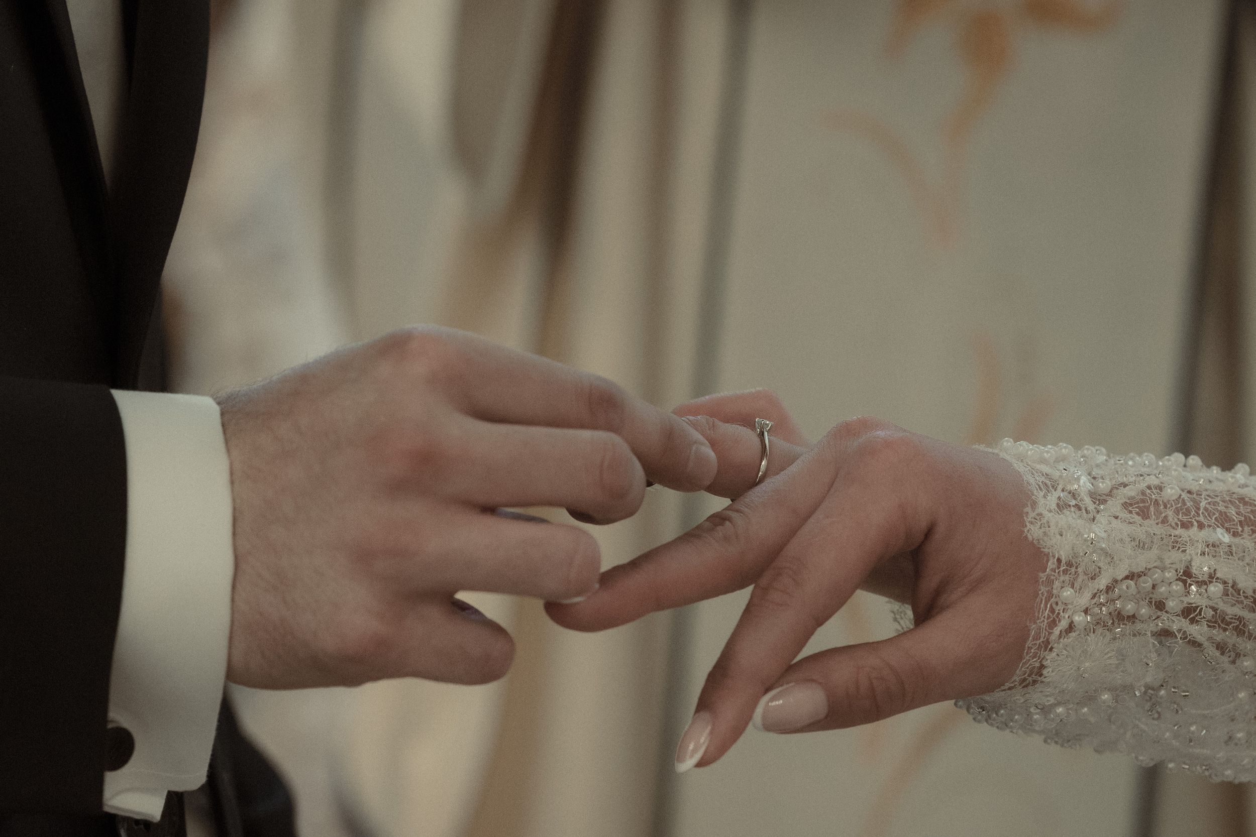 A close-up shot of hands exchanging wedding rings during a marriage ceremony.