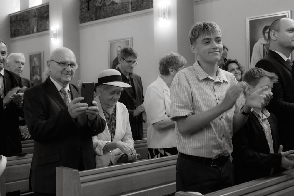 Black and white photograph of people standing in church pews during a worship service.