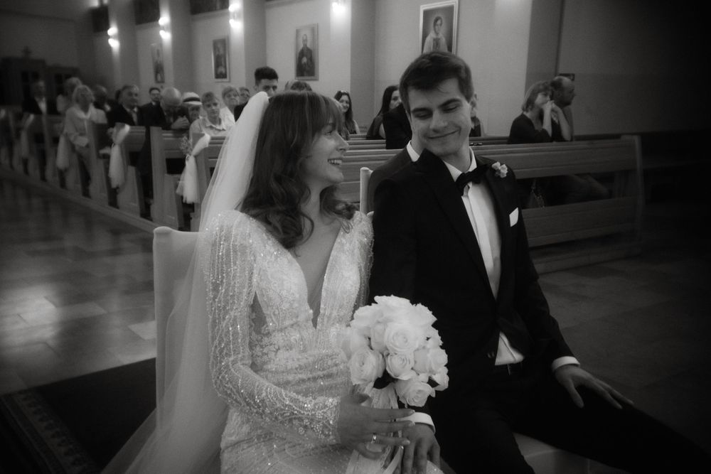 A black and white photograph of a bride and groom during their wedding ceremony inside a church.