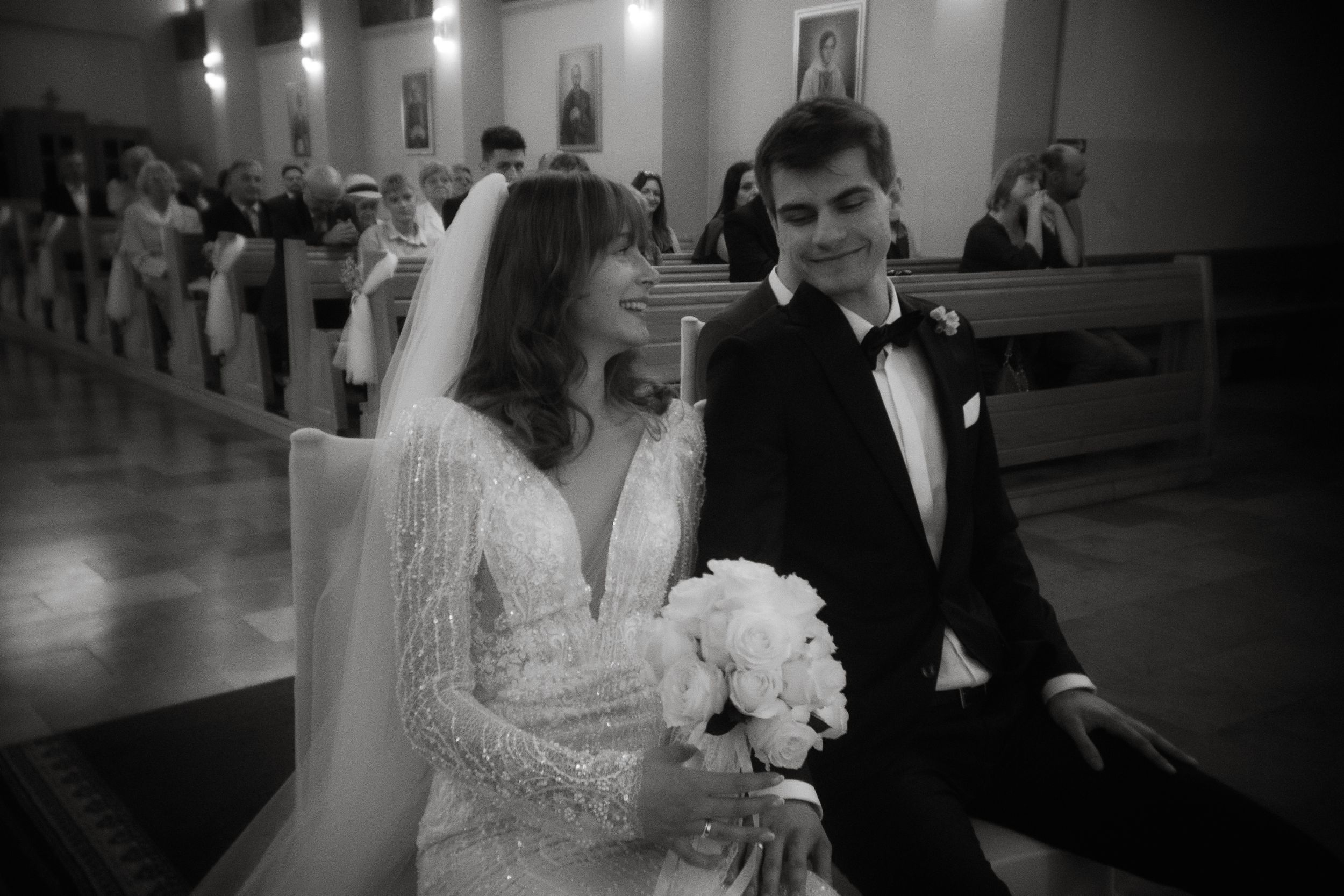 A black and white photograph of a bride and groom during their wedding ceremony inside a church.