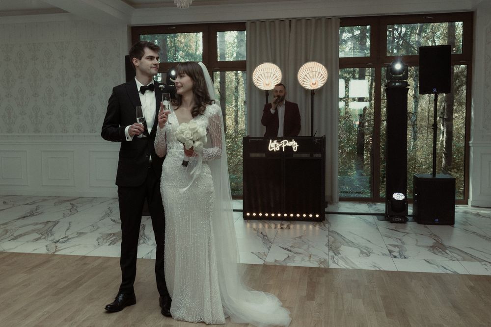 A couple shares an intimate moment during their wedding ceremony in a modern venue with marble floors and glass walls.