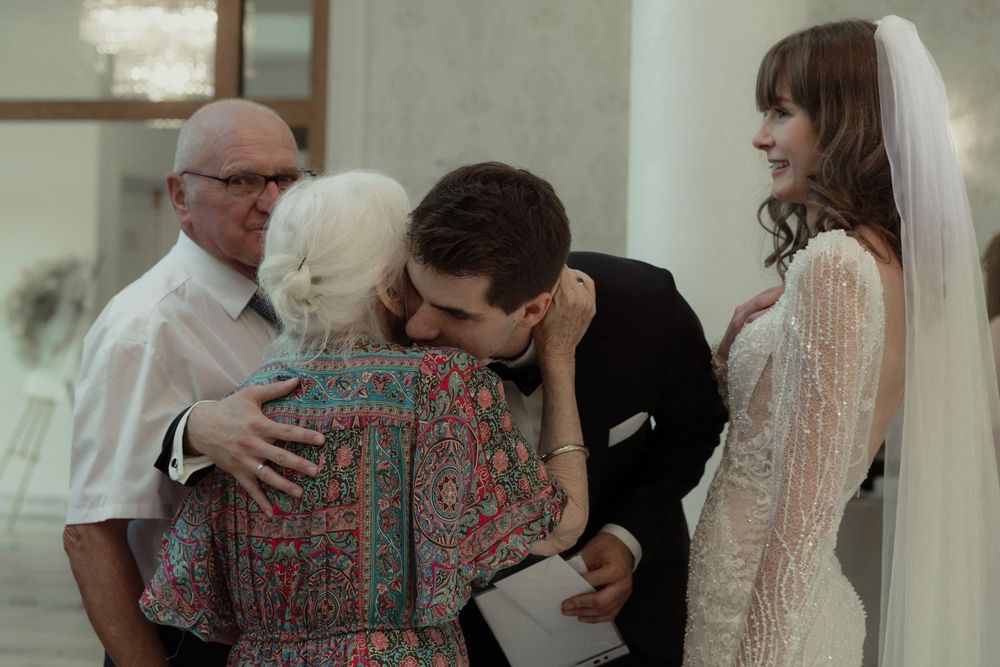 An emotional moment shared between people at a wedding ceremony, with a bride in white standing nearby.