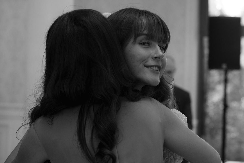 The black and white image shows a person with dark bangs looking down while posing against a light background.