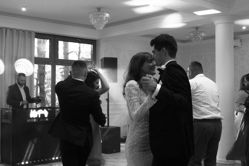 A romantic black and white photo captures two people dancing close together at an indoor celebration.