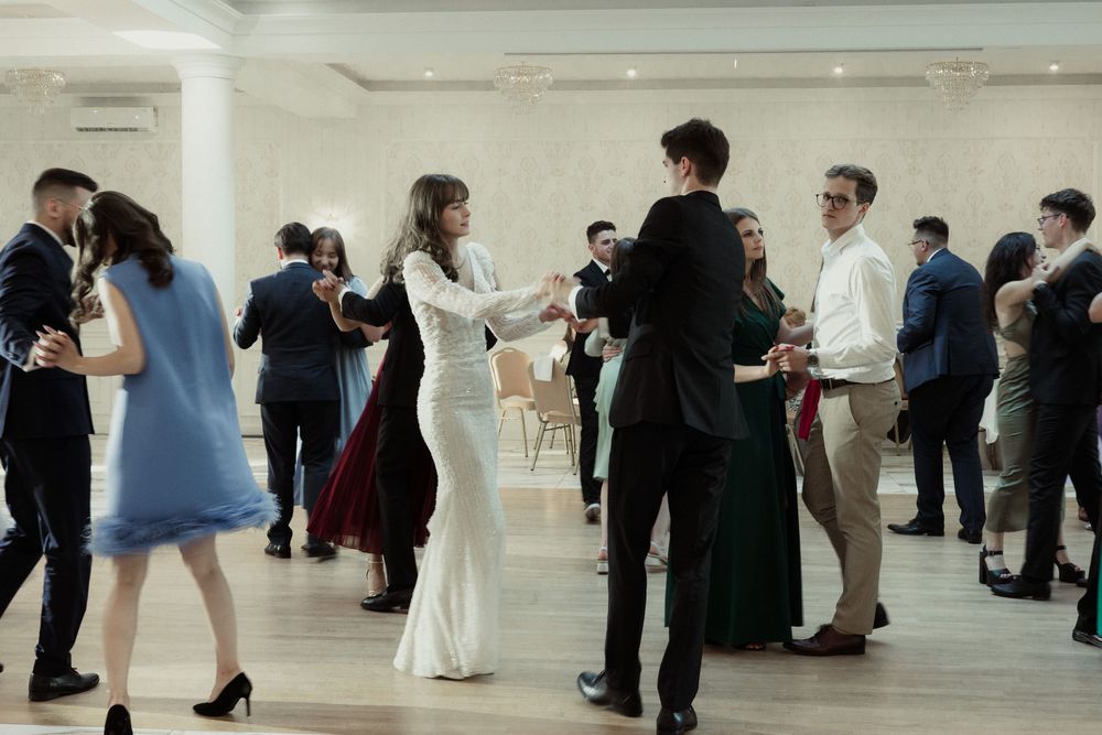 People browse artwork displays in a modern white gallery space with bright lighting and polished floors.