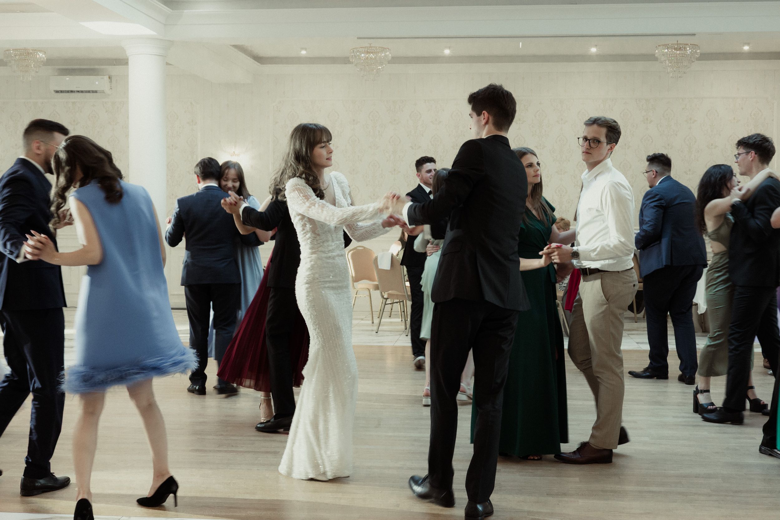 People browse artwork displays in a modern white gallery space with bright lighting and polished floors.