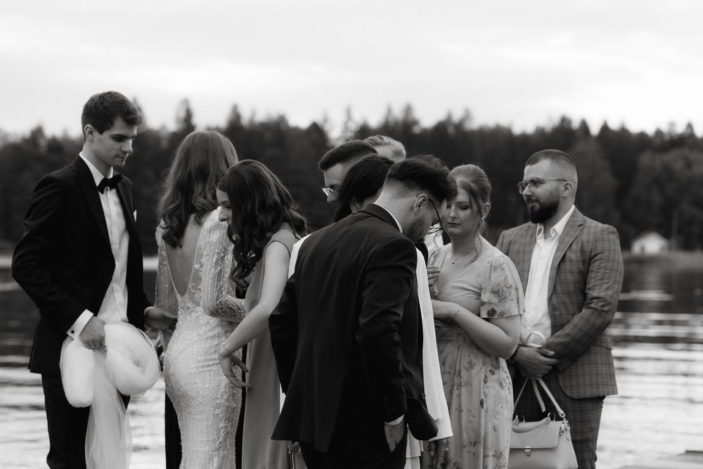 Black and white wedding photographs arranged horizontally showing outdoor ceremony moments by a waterfront.