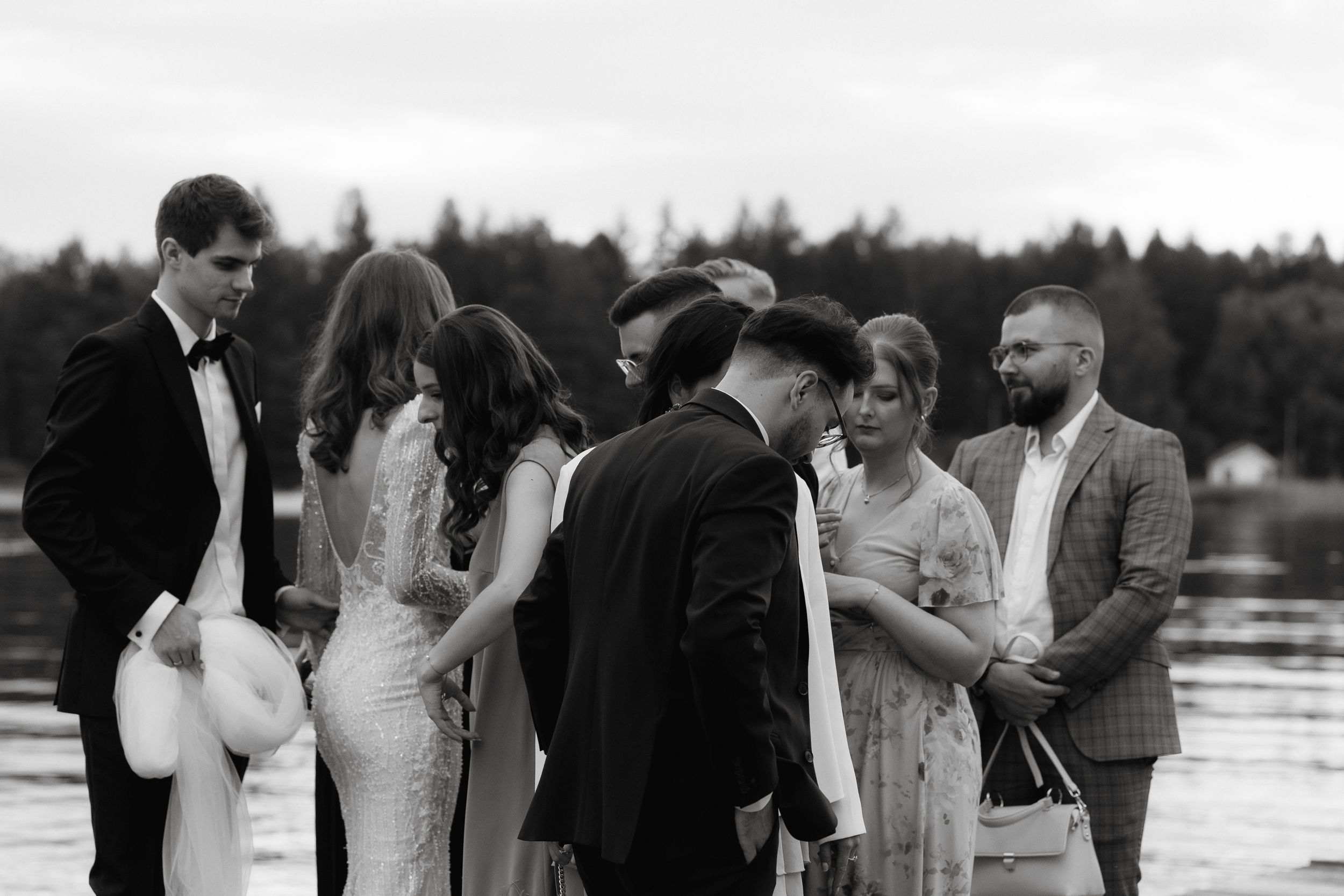 Black and white wedding photographs arranged horizontally showing outdoor ceremony moments by a waterfront.