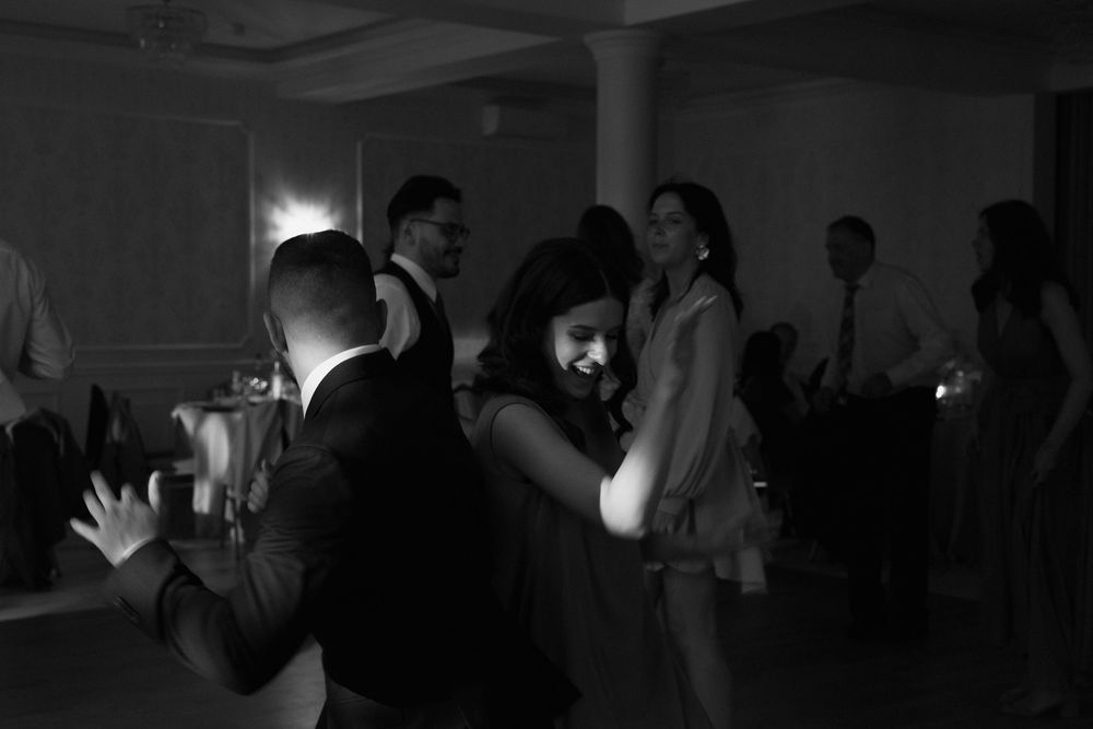 Dark silhouettes of people dancing against a dimmed background during a party or celebration.
