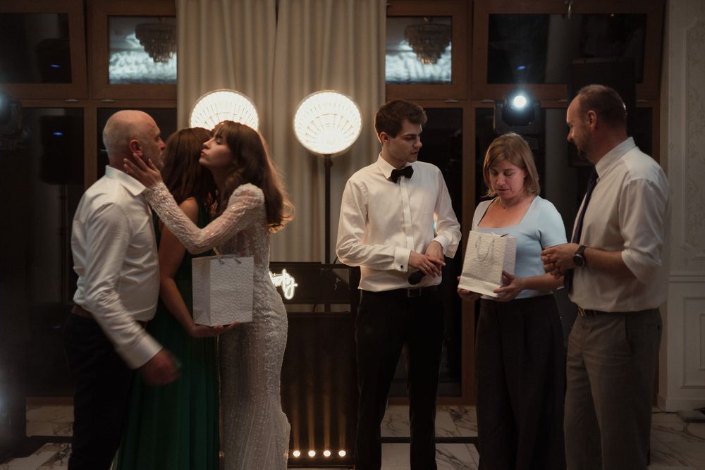 Five people having a conversation in an elegant evening setting with glowing round pendant lights.